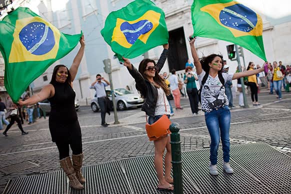 Brazilians holding their country`s flag play in the updraft of a subway vent outside Lisbon`s Brazilian consulate.