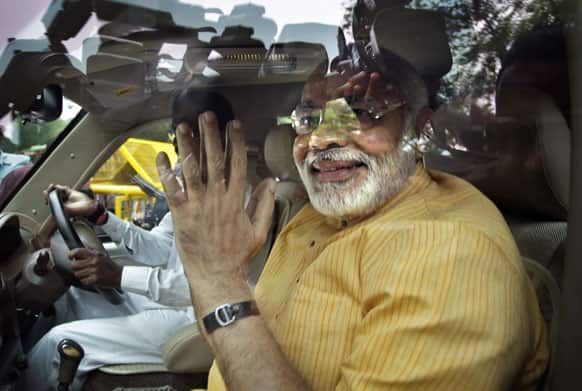 Chief Minister of Indian state of Gujarat Narendra Modi greets media person sitting inside his car as he leaves after meeting Bharatiya Janata Party senior leader L.K.Advani, in New Delhi.