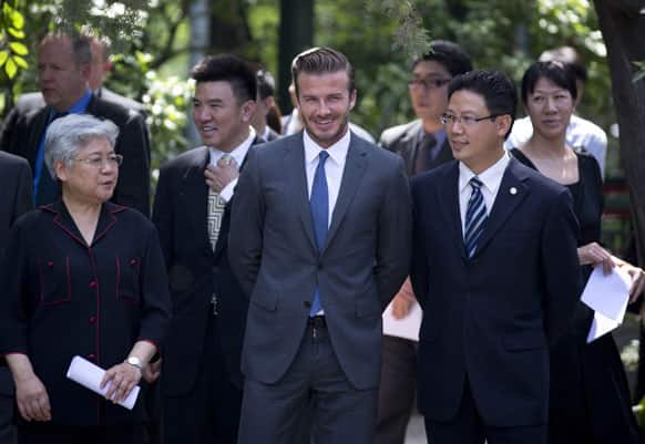 David Beckham and Tang Wensheng, chairperson of China`s Soong Ching Ling Foundation, walk with Chinese officials upon arrival for a charity event in Beijing.