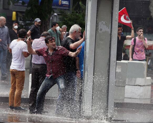A protester throws a stone toward police as Turkish riot police spray water cannon at demonstrators who remained defiant after authorities evicted activists from an Istanbul park, making clear they are taking a hardline against attempts to rekindle protests that have shaken the country, in city`s main Kizilay Square.