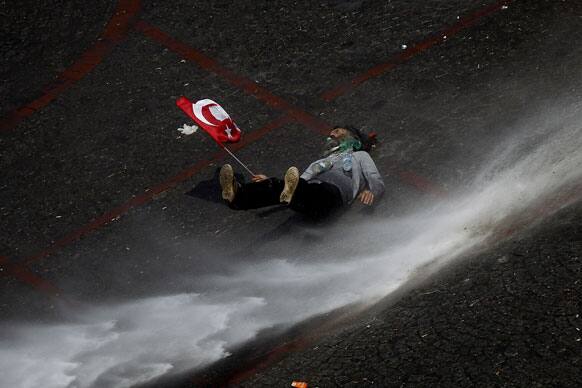 A protester holding a Turkish flag is thrown off his feat by a stream of water from a police water canon during clashes in Taksim square in Istanbul.