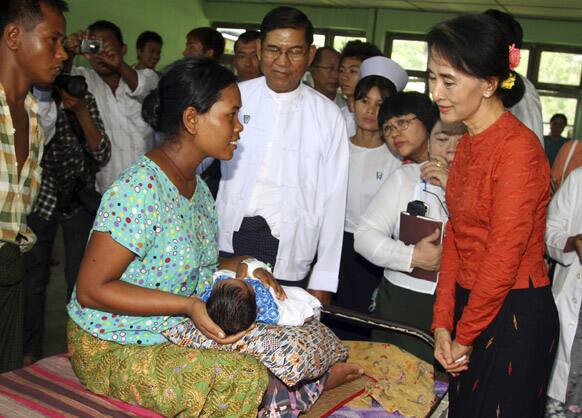 Myanmar opposition leader Aung San Suu Kyi talks with a mother as her child is treated for Dengue fever at a hospital in Kawhmu township, in Myanmar.