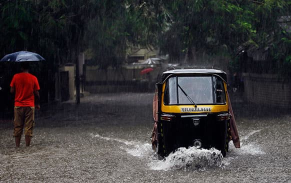 An Indian man rides his auto rickshaw through a flooded road after a heavy spell of rain in Mumbai, India. Heavy rains continued to lash India’s commercial capital Sunday.