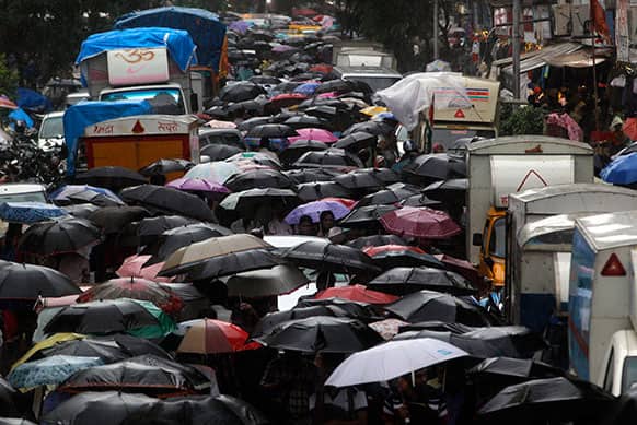 People make their way along a crowded street during heavy rain, near to a train station in Mumbai.