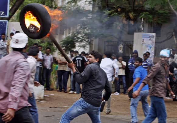 A student holds a burning tire with a rod during a protest demanding creation of a new state named “Telangana” in Hyderabad.