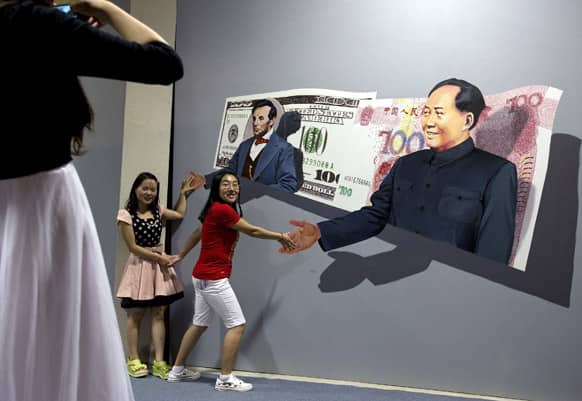 Chinese girls pose with a 3D painting that shows former Chinese leader Mao Zedong and former US President Abraham Lincoln popping up on banknotes at the 798 Art District in Beijing.