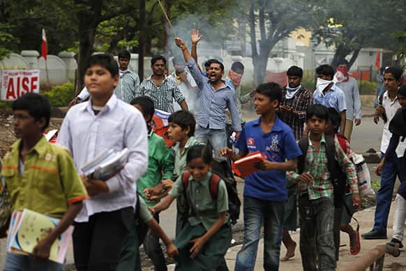 Children returning from school walk past protestors supporting the demand for the creation of a new ‘Telangana’ state as they shout slogans at police in Hyderabad.