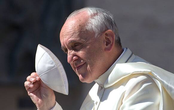 Pope Francis holds his skullcap as he arrives in St. Peter`s square at the Vatican for his weekly general audience.