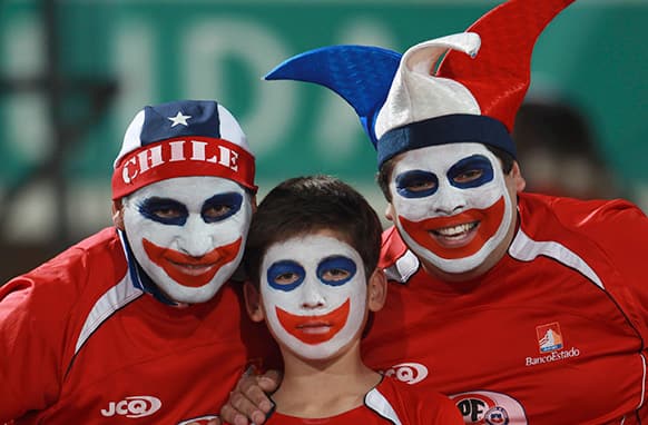 Chile soccer fans wearing face paint pose for a photo before the start of a 2014 World Cup qualifying soccer match with Bolivia in Santiago, Chile.