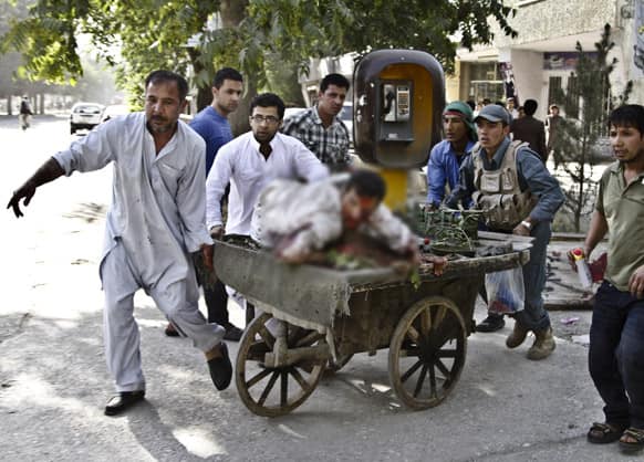 Afghans rush a wounded man to receive treatment, after a suicide car bomber struck outside the Afghan Supreme Court in Kabul.