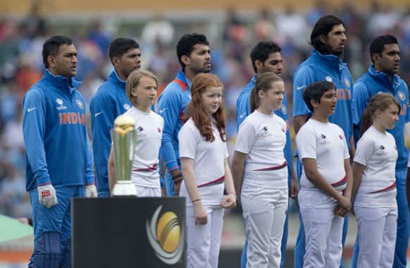Members of the India team listen to their national anthem as they stand with young mascots before the ICC Champions Trophy group B cricket match between India and West Indies at The Oval cricket ground in London.