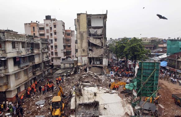 Rescue workers search for trapped people after a residential building collapsed in Mumbai. A portion of a four-story building in India`s financial capital collapsed in heavy monsoon rains, killing some people Tuesday.
