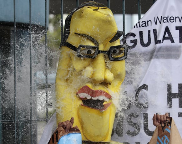 A protester wearing a mask of Philippine President Benigno Aquino III is hit by plastic bags with water as they hold a rally in Manila.