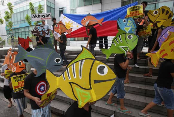 Protesters wearing fish-shaped hats walk outside the Chinese Consulate during a rally in suburban Makati, south of Manila, Philippines.