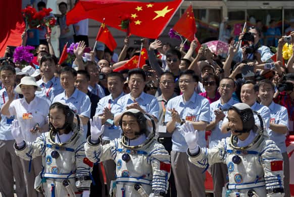 China`s astronauts from left, Wang Yaping, Zhang Xiaoguang and Nie Haisheng wave to the media as they leave the Jiuquan satellite launch center near Jiuquan in western China`s Gansu province.