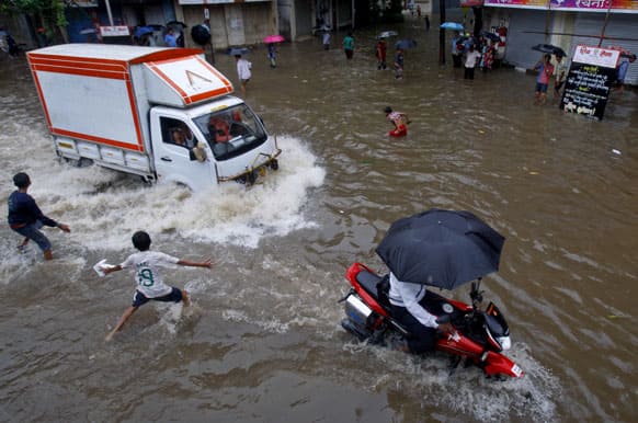 Children play as vehicles ply through a flooded street during monsoon rains in Mumbai. Heavy rains disrupted rail and road traffic in India`s commercial capital Monday, affecting normal life, news reports said.
