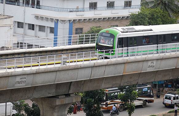 Traffic moves underneath as a Namma Metro (Our Metro) train pass through a residential area during its safety trial run in Bangalore.