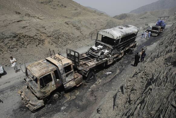 Pakistani security personnel and villagers look at gutted NATO trucks in Pakistan`s tribal region of Khyber.