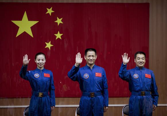 China`s astronauts from left, Wang Yaping, Nie Haisheng and Zhang Xiaoguang wave from behind glass enclosure as they arrive to meet the press at the Jiuquan satellite launch center near Jiuquan in western China`s Gansu province.