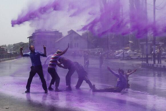 Policemen use colored water from a water cannon to disperse state government workers during a protest in Srinagar.
