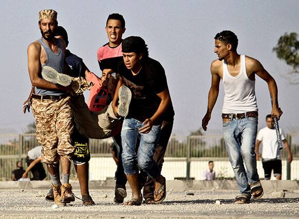 Libyans help a wounded man during fighting outside the office of the Libya Shield pro-government militia in Benghazi, Libya.