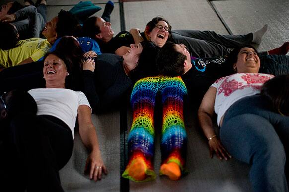 People laugh as they take part in performing a group exercise during a laughter yoga class in St Albans, England.