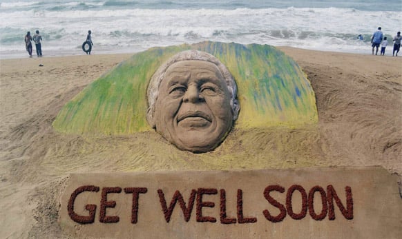 Beach goers walk past a sand sculpture created by Indian artist Sudarsan Pattnaik wishing speedy recovery to former South African President Nelson Mandela on the Bay of Bengal coast in Puri, Orissa state.