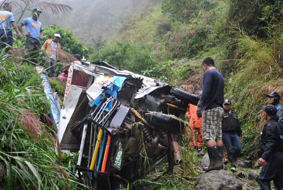 Police officers inspect the wreckage of a van that veered off a mountain road in the remote Buguias town in Benguet province, northern Philippines.