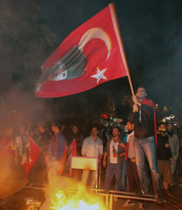 A Turkish protester waves a national flag with a poster of Turkey`s founder Kemal Ataturk at a barricade before they clash with riot police stationed on the John F. Kennedy Street, in front of the US embassy in Turkish capital, Ankara.