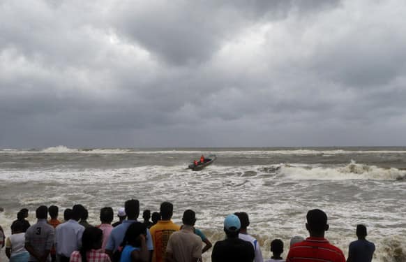 Sri Lankan people watch a rescue boat search for missing fishermen in Dehiwala on the outskirts of Colombo. Heavy wind and rains caused by the southwestern monsoon killed five people and left 17 fishermen missing along Sri Lanka`s coast Saturday, an official said.