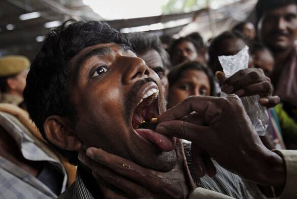 A member of the Goud family administers “fish medicine” to an asthma patient in Hyderabad. Started by the Bathini Goud family, the therapy is a secret formula of herbs. The herbs are inserted in the mouth of a live sardine, or murrel fish, and slipped into a patient`s throat.