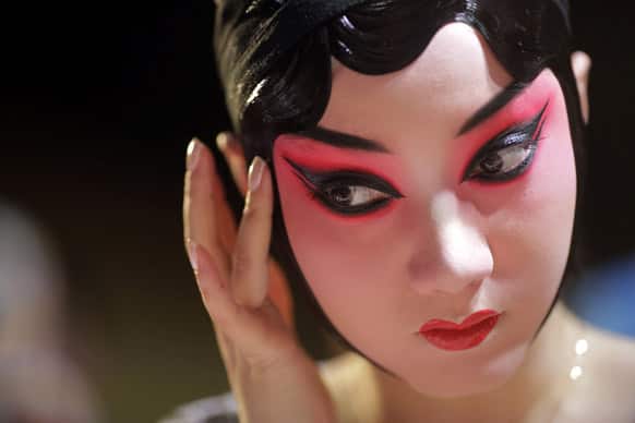 A Beijing Opera actress applies makeup at the back stage before the show begins in Shanghai, China.