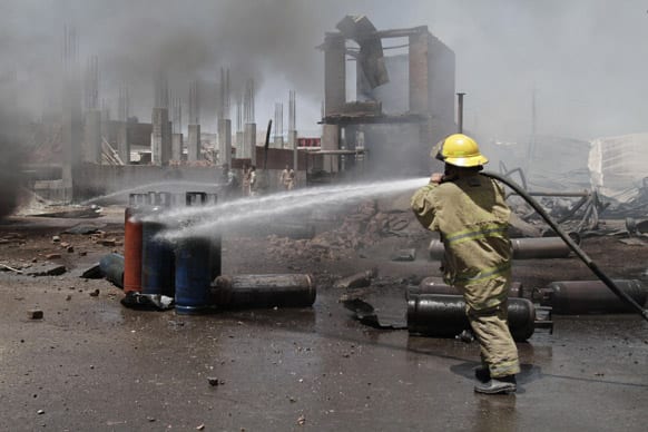 An Afghan firefighter sprays water at the scene of a propane gas explosion accident in Jalalabad, east of Kabul, Afghanistan. About 30 shops at the market were burnt down in the fire.