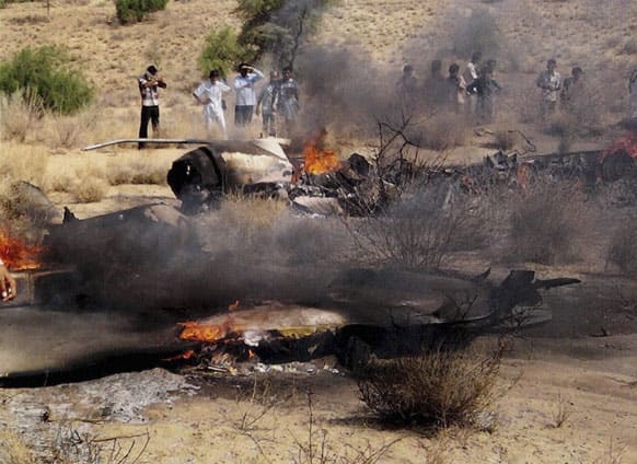 People watch the burning wreckage of a MiG-21 jet of the Indian Air Force near Sodiyar village in Barmer district of the western Indian state of Rajasthan. No casualties were reported as the pilot of the fighter jet ejected safely, according to a local news agency.