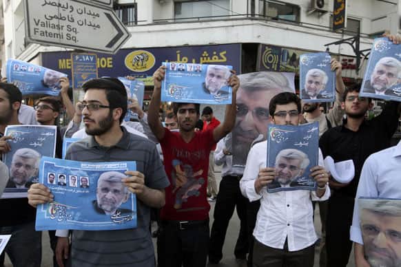 Supporters of the Iranian presidential candidate Saeed Jalili, shown in the posters, who is also Iran`s top nuclear negotiator, attend a street campaign, in Tehran, Iran.