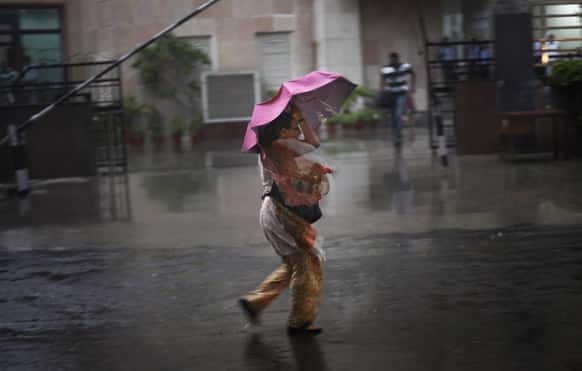 A woman struggles with her umbrella against a strong wind during a sudden heavy downpour in New Delhi.