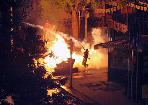 A protester throws back a tear gas canister toward riot police stationed on the John F. Kennedy Street, in front of the US embassy in the Turkish capital, Ankara.