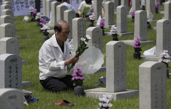 A South Korean Kang Duk-sung, 71, holds flowers on his knees in front of the gravestone of his relative Marine Kang Chu-young who died during the 1950-1953 Korean War on the South Korea`s Memorial Day at the National Cemetery in Seoul, South Korea.
