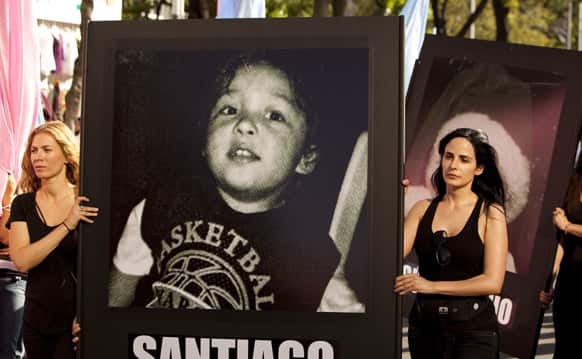 Women carry photographs of children who died in a 2009 daycare fire as they protest on the fourth anniversary of the blaze in Mexico City.