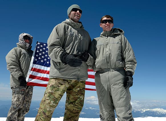 Capt. Matthew Blumberg, center, re-enlists Spc. Austin Wheeler, right, at the top of Mt. Adams with Mt. Rainier in the background.