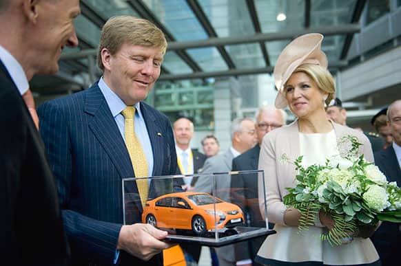 Dutch King Willem-Alexander second left, and Queen Maxima are presented with anorange model of the hybrid car Opel Ampera by CEo of Adam Opel AG, Karl-Thomas Neumann, left, , in Ruesselsheim, Germany.