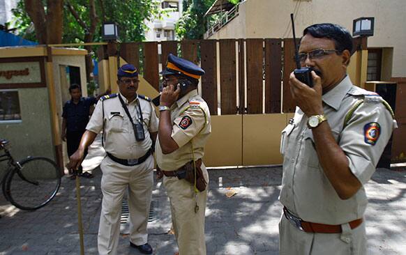 Police men speak on a wireless radio as they stand outside a complex that houses the home of Bollywood actress Jiah Khan in Mumbai.