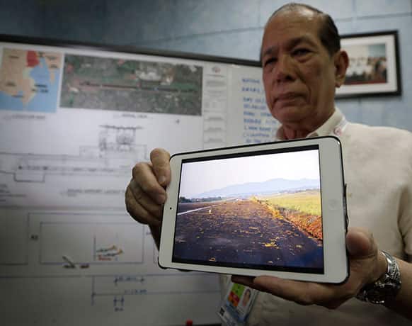 Civil Aviation Authority Deputy Director General John Andrews displays a photo from his notepad showing the grass that spilled on the runway during a news conference in Manila.