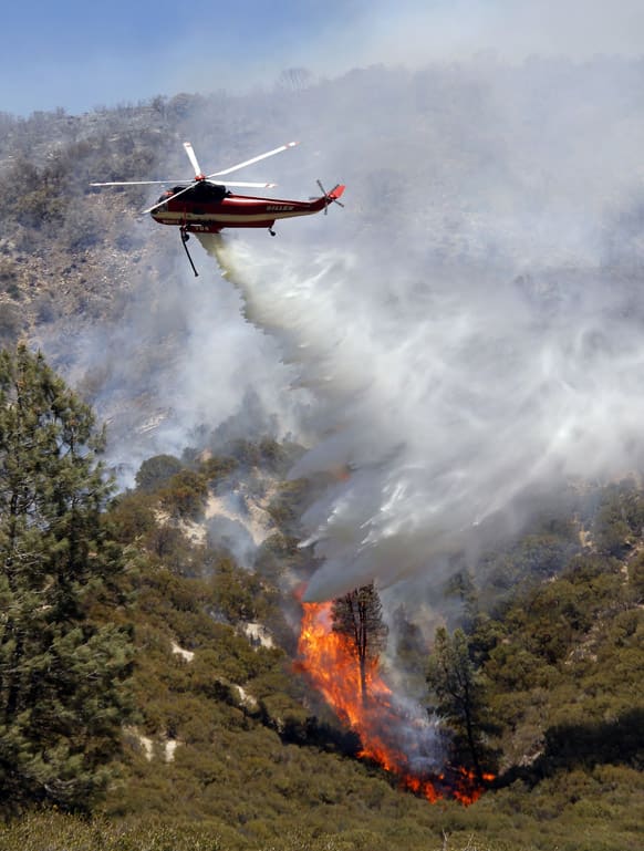 A helicopter drops water on hill fire to fight what has been called the Powerhouse fire in the rural community of Lake Hughes in northern Los Angeles County. Calif.