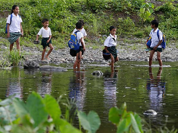 Elementary pupils cross a river on the way to attend the opening of classes for the school year 2013-2014 Monday, June 3, 2013 at a remote village in Rodriguez township, Rizal province, about 50 kilometers (33 miles) east of Manila, Philippines.