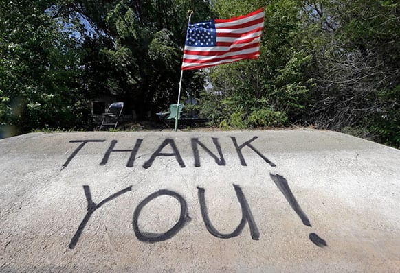 Strong wind snaps the American flag above a message painted on a boat launch ramp on the shore of Hughes Lake, where helicopter pilots picking up water from the lake can see it, as the fight against what has been called the Powerhouse fire in Lake Hughes, Calif., continues late Sunday afternoon.