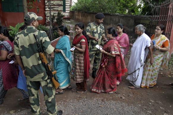 Border Security Force soldiers check identities of voters on queue during a by-election at the Indian Parliamentary constituency of Howrah, outskirts of Kolkata.