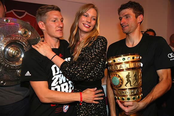 Bayern players Bastian Schweinsteiger, left, and Thomas Mueller, right, celebrate with Schweinsteiger`s girl friend Sarah Brandner at the party after Bayern won the German Soccer Cup, DFB-Pokal, final against VfB Stuttgart in Berlin.