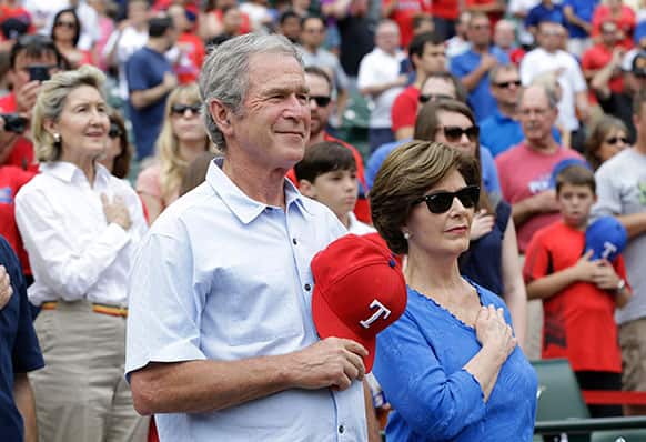 Former President George W. Bush stands during the national anthem with his wife Laura Bush before a baseball game between the Kansas City Royals and Texas Rangers in Arlington.