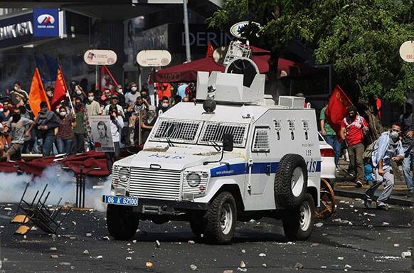 A Turkish protester, right, throws a stone at police vehicle as the protesters clash with security forces in Ankara, Turkey.